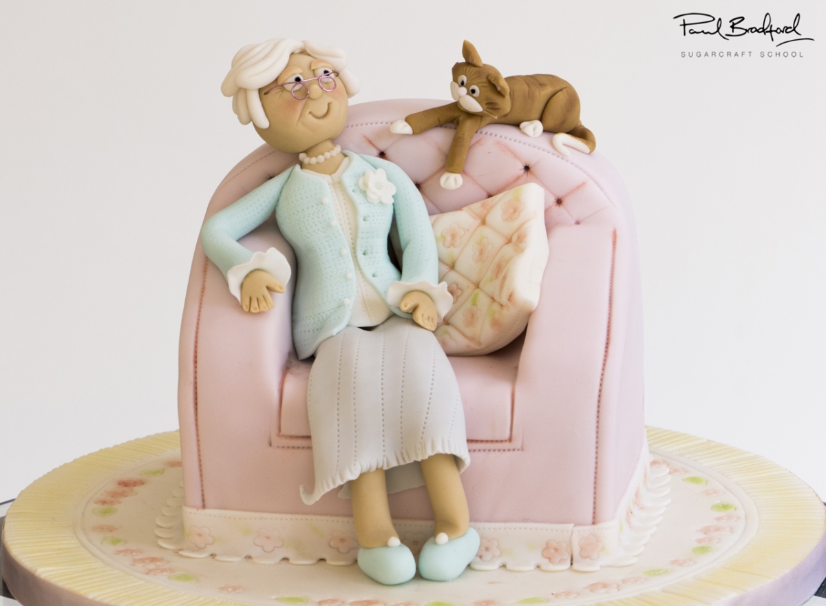 old lady sitting in here chair with a cake cake